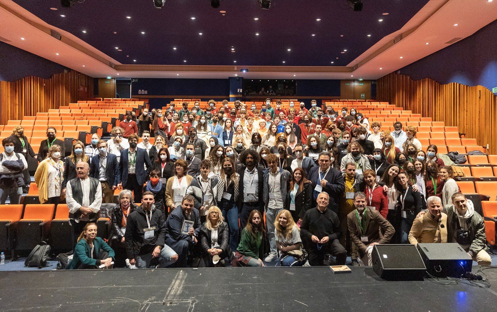 un folto gruppo di persone in un'aula magna in posa